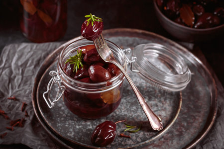 Marinated plums with spices in glass jar on the kitchen tableの写真素材