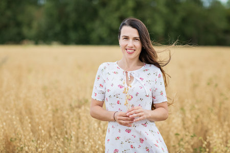 A brunette woman in a white dress stands in a fieldの写真素材