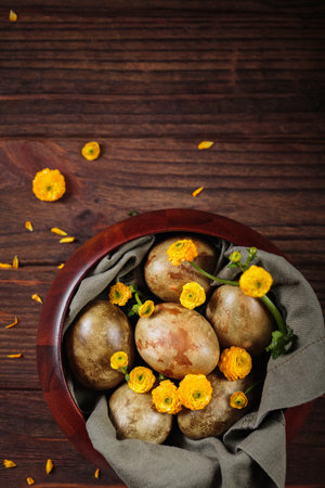 Overhead shot of dyed Easter eggs and yellow flowers in a bowlの写真素材