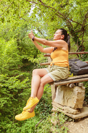 Woman relaxing on wooden bench in summer forestの写真素材