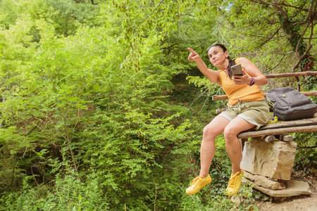 Woman using smartphone for pathfinding in forestの写真素材