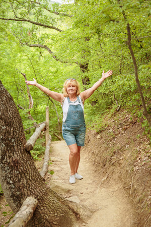 Middle aged woman walking along forest path with backpackの写真素材
