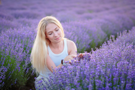Woman walking between rows of lavender flowers and posingの写真素材