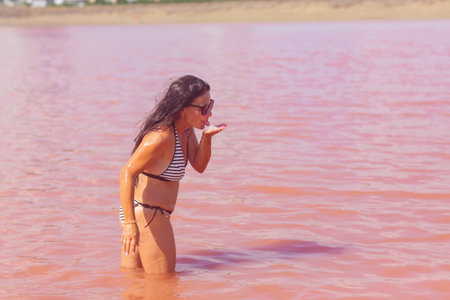Woman tasting water in a pink salt lakeの写真素材