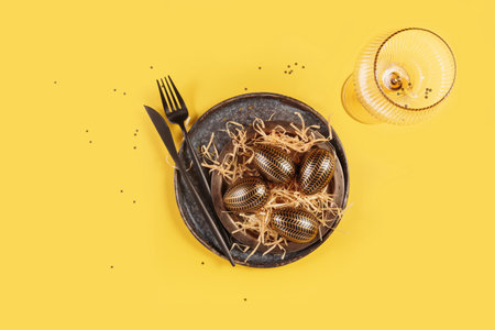 Table place setting and festive easter decor on yellow background