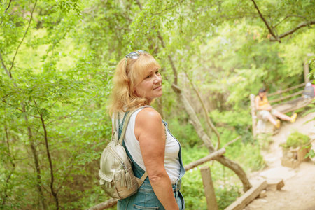 Middle aged woman with backpack walking along forest pathの写真素材