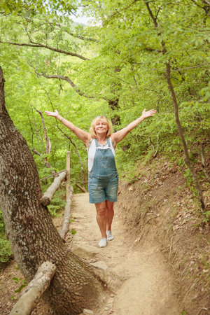 Middle aged woman walking along forest pathの写真素材