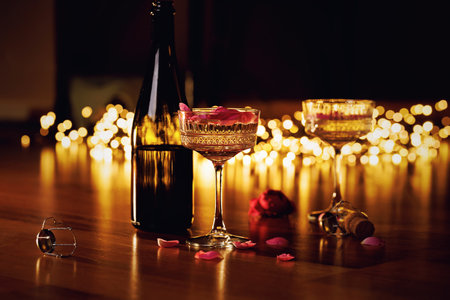 Romantic champagne celebration with rose petals and warm lightsの写真素材