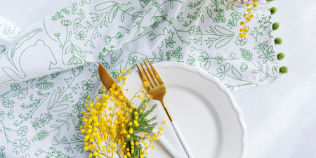 Spring table arrangement with mimosa flowers and golden utensilsの写真素材
