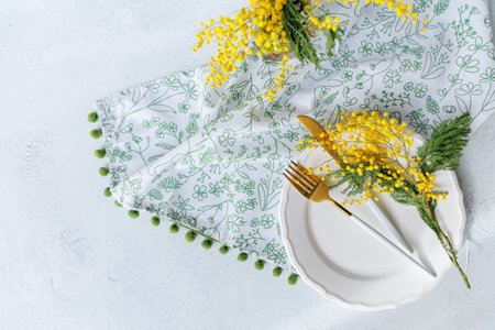 Stylish spring table with mimosa flowers and golden flatwareの写真素材