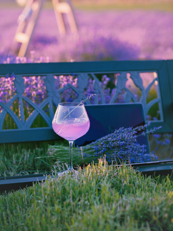 Bouquet of flowers and summer cocktail on bench among lavender fieldの写真素材