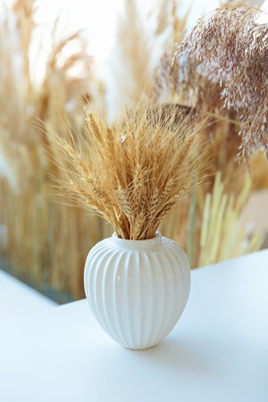 Elegant dried wheat bouquet in a white ceramic vaseの写真素材