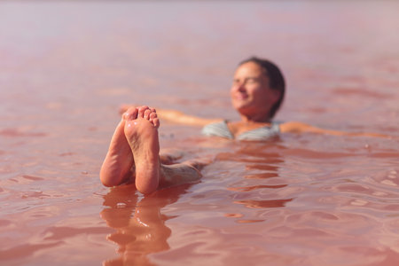 Prominent feet focus of woman in pink lakeの写真素材