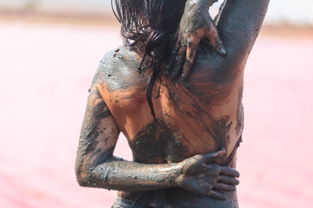 Womans back covered in healing mud near pink lakeの写真素材