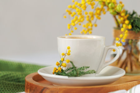 Freshly brewed coffee with mimosa flowers on a wooden trayの写真素材