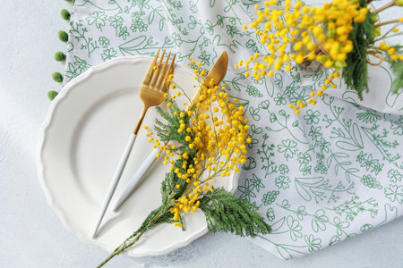 Elegant spring dining table with mimosa flowers and golden cutleryの写真素材