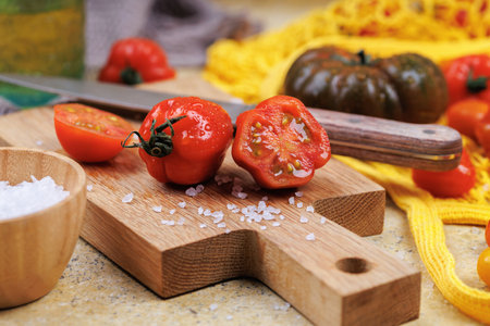 Fresh heirloom and cherry tomatoes with knife and salt on kitchen boardの写真素材