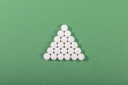 Pyramid of white tablets on green background
