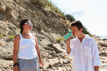 Mother and son sharing a drink by the beachの写真素材