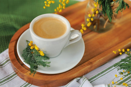 White cup of coffee with mimosa flowers on a spring morningの写真素材