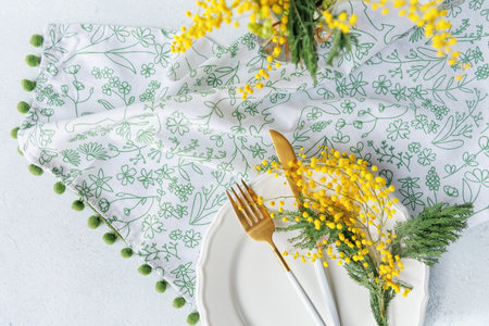 Spring table setting with mimosa flowers and golden cutleryの写真素材