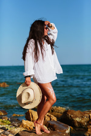 Mature woman standing on beach with hat and sunscreen designの写真素材