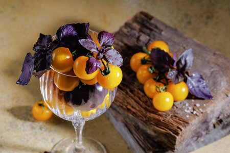 Top view of yellow tomatoes with wet basil on rustic backgroundの写真素材