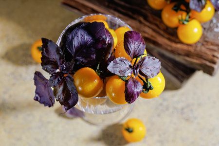 Above view of yellow cherry tomatoes and basil in glassの写真素材