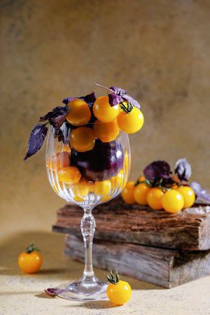 Yellow cherry tomatoes with purple basil in glass on rustic wooden backgroundの写真素材