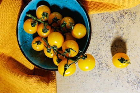 Flat lay of fresh cherry tomatoes in rustic ceramic bowlの写真素材