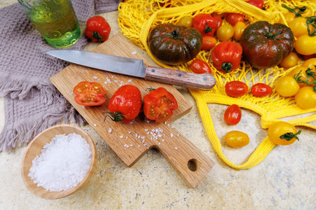 Fresh tomatoes with salt and knife on wooden board for healthy cookingの写真素材