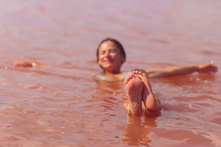 Focused feet of woman floating in pink lake