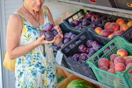 Mature woman choosing fruit in street storeの写真素材