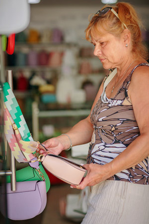 Mature woman chooses a handbag in the storeの写真素材