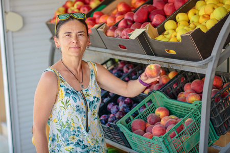 Mature woman choosing fruit in street storeの写真素材