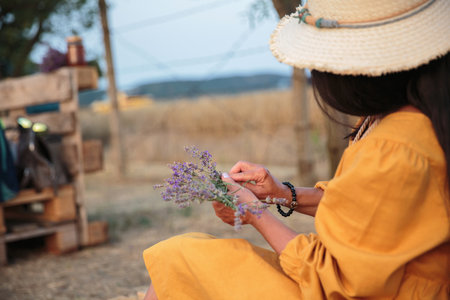 Woman crafting lavender bouquet in rural field..の写真素材