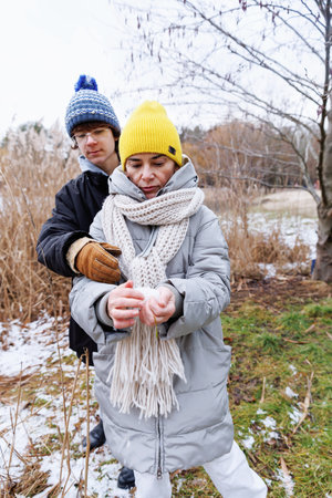 Teen son helping mother form snowball during winter walk
