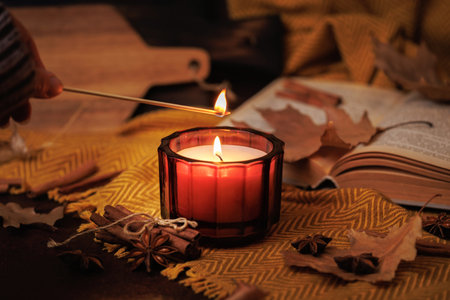Lighting Candle with Matchstick in Autumn Settingの写真素材