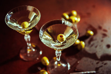 Elegant Martini Glass with Green Olives and Warm Bokeh Lightsの写真素材