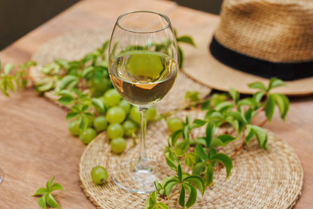 White Wine Glass with Grapes and Leafy Decor Outdoorsの写真素材