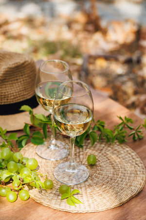 Outdoor Wine Scene with Hat and White Wine Glassesの写真素材