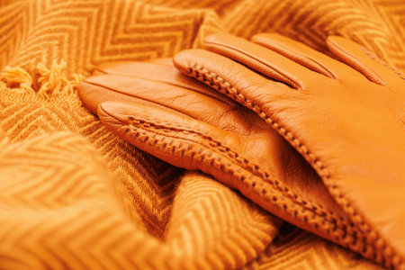 Soft wool scarf with orange leather gloves close-upの写真素材