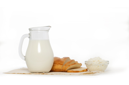Glass jug with milk, bowl of cottage cheese and white bread on wの写真素材