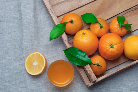 Oranges and tangerines in a wooden box on canvas. Orange juice.の写真素材