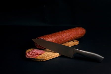sausage salami on a cutting board and knifeの写真素材