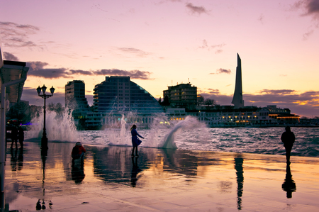 Sevastopol, Crimea, Russia - January 31, 2018: People walking on wet seafront at windy stormy weather at sunset.のeditorial素材