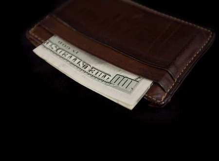 WALLET WITH $100 BILL ISPLATED ON BLACK BACKGROUND