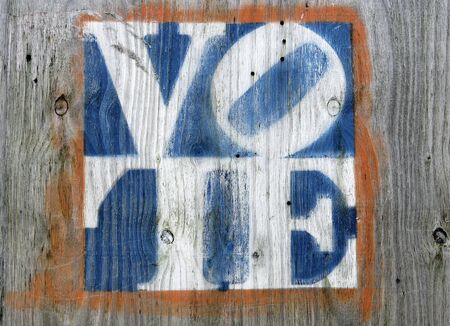 faded colors vote sign on a weathered gray plywoodの写真素材