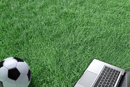laptop and a soccer ball on the green grass texture  of a fresh lawn fieldの写真素材