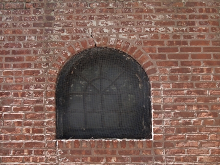 old fashion window in the weathered stained red brick wall backgroundの写真素材